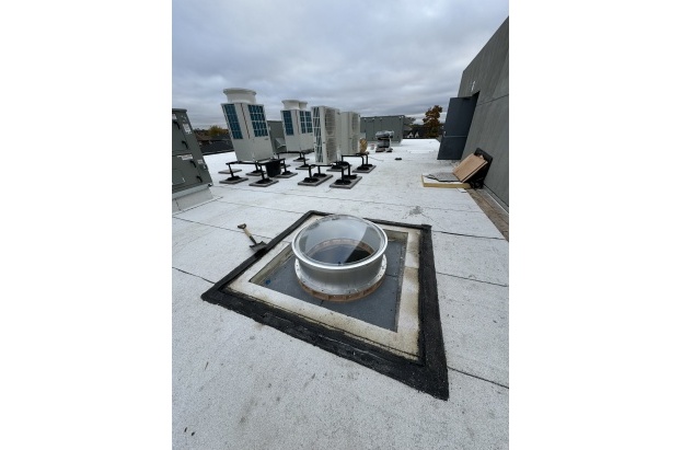 circular skylight with aluminum curb installed on a roof.