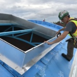 Artistic Skylight technician applying weatherstripping on to aluminum curb